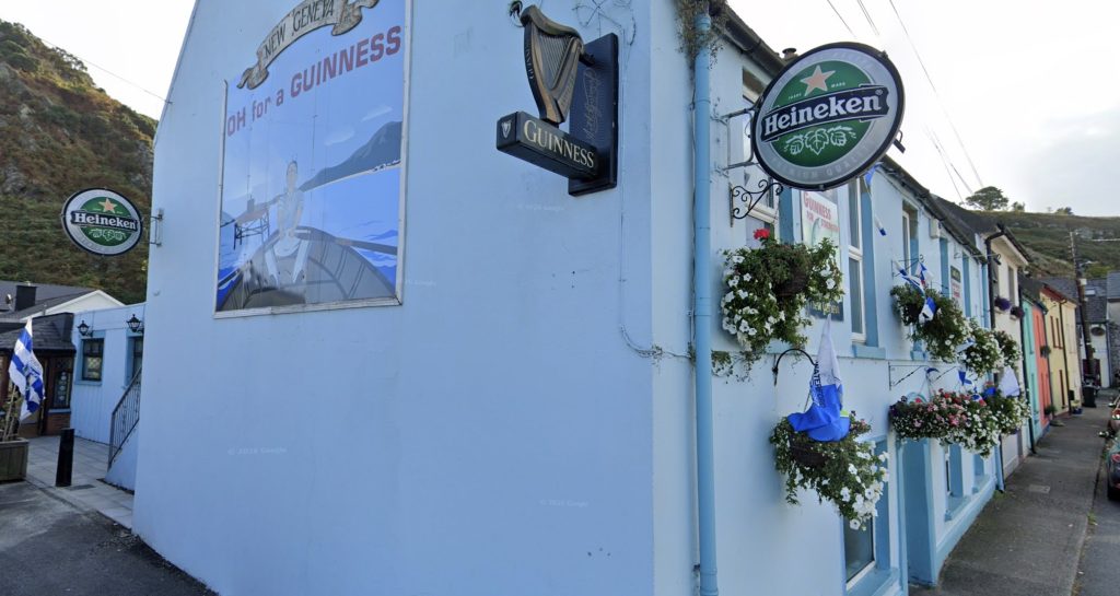The corner of Furlong's New Geneva, with Guinness and Heineken signs and flower baskets above Dobbyn's Street.